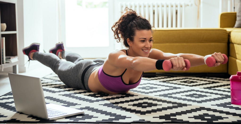 Young woman exercising at home in a living room.