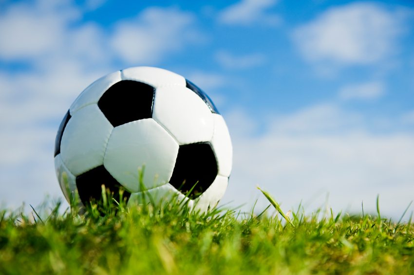 Soccer ball on grass with sky background